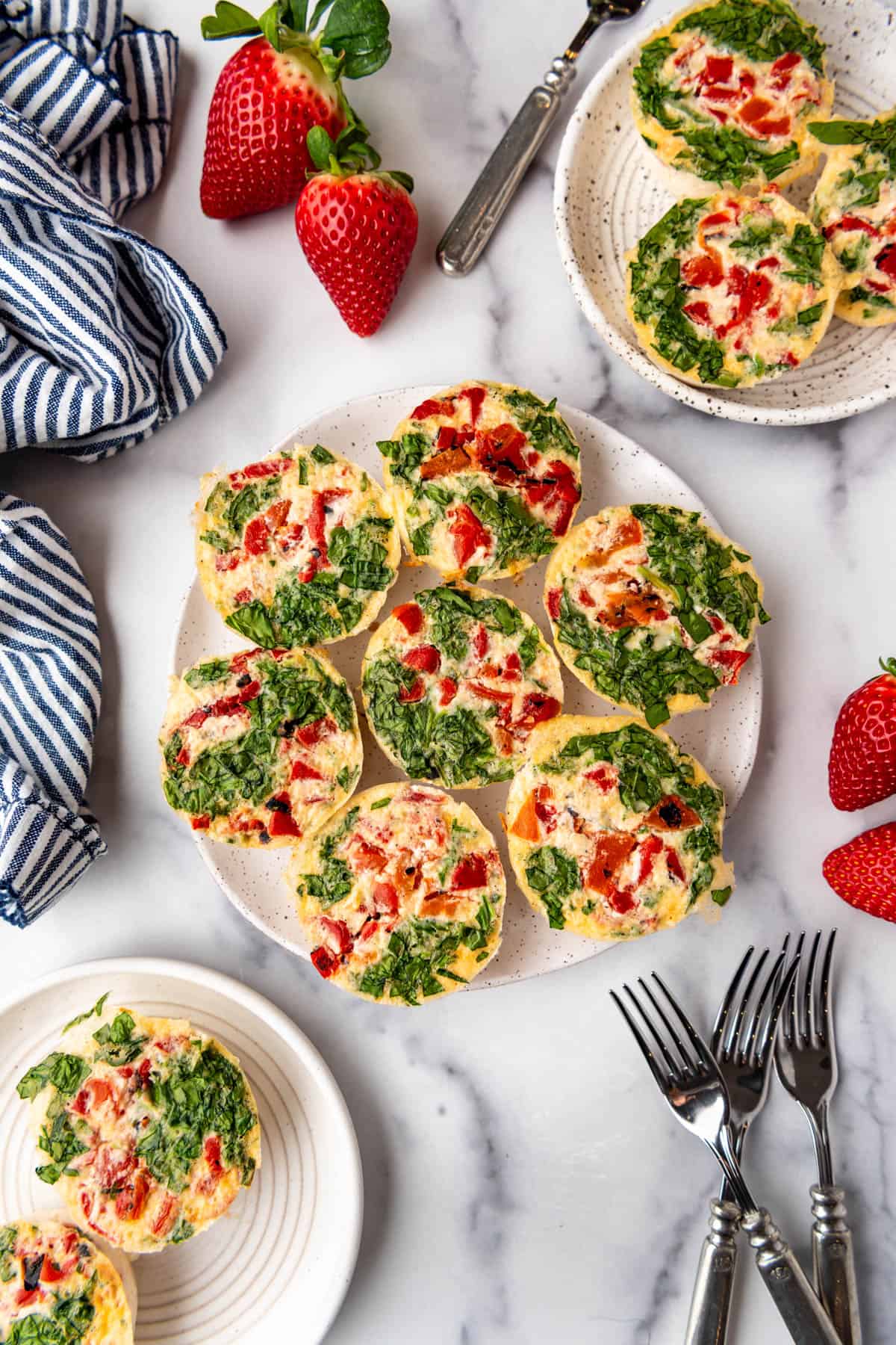 An overhead image of spinach and roasted red pepper egg white bites on plates.