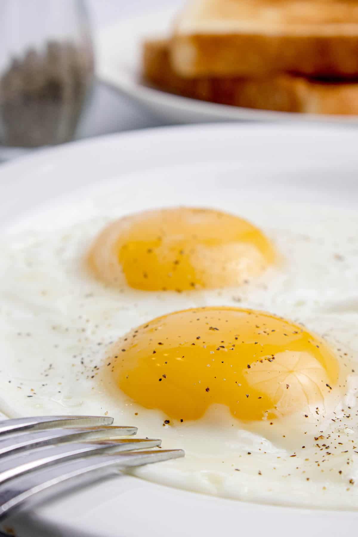 A close up image of sunny side up eggs on a plate.