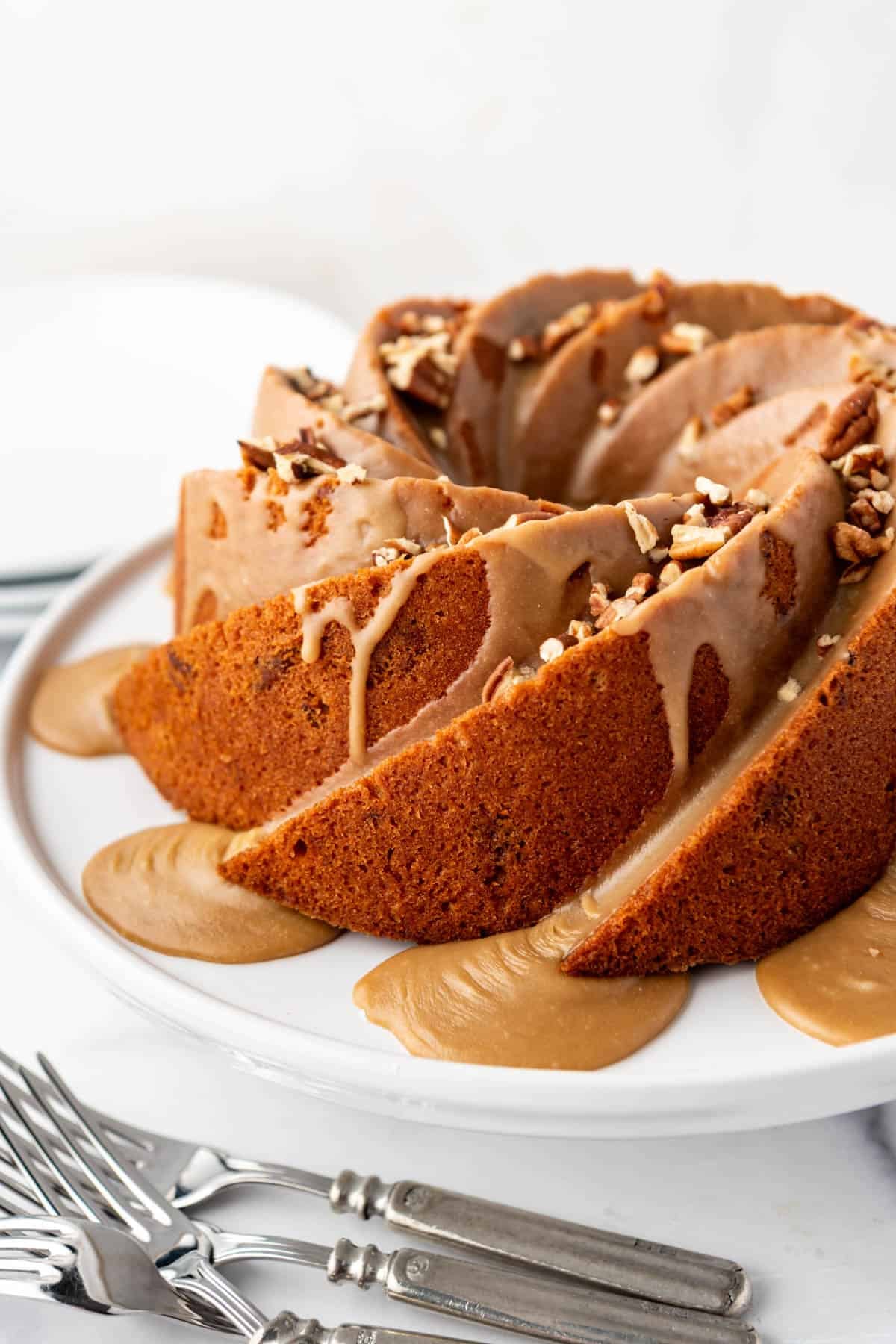 An image of a pecan praline bundt cake on a white cake stand.