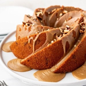 An image of a pecan praline bundt cake on a white cake stand.