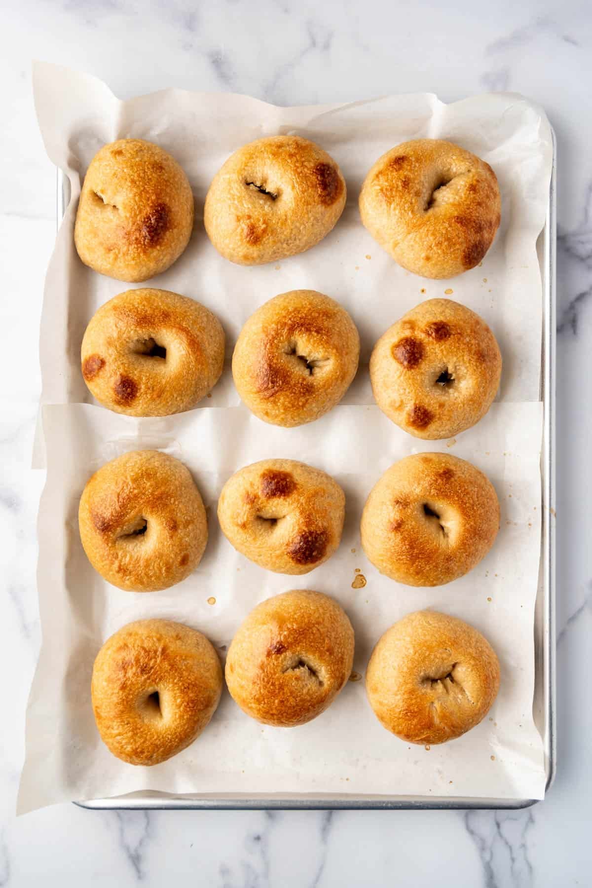 Baked sourdough bagels on a baking sheet.
