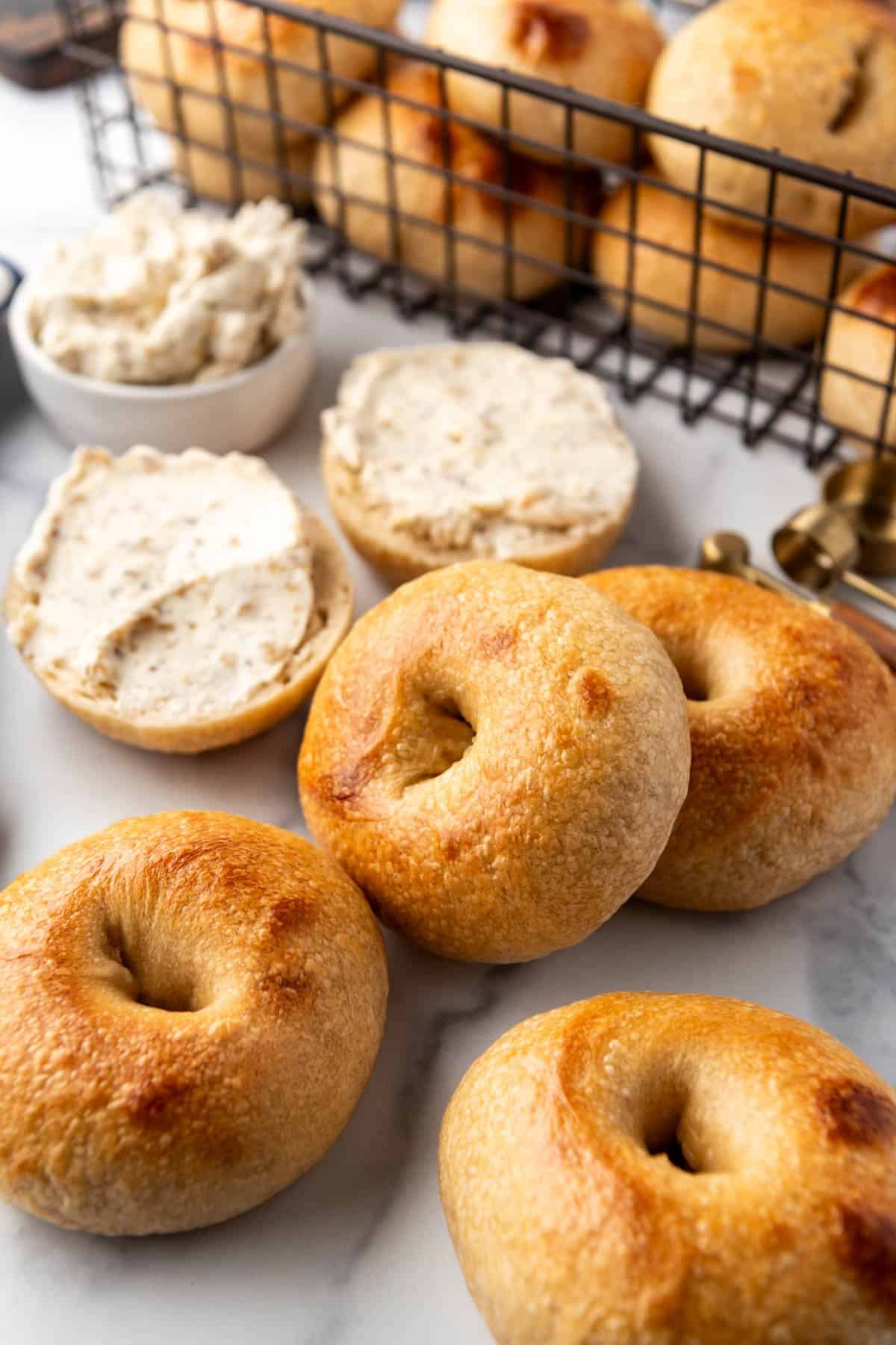 Sourdough bagels scattered on a white marble surface.