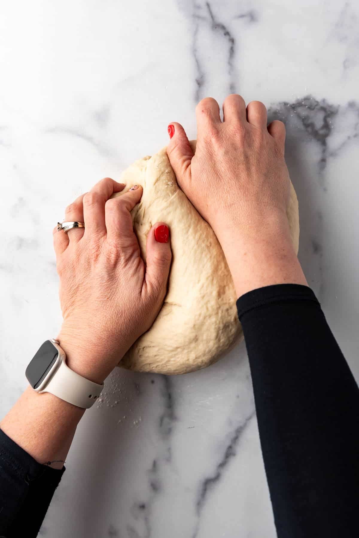 Hands kneading bagel dough.