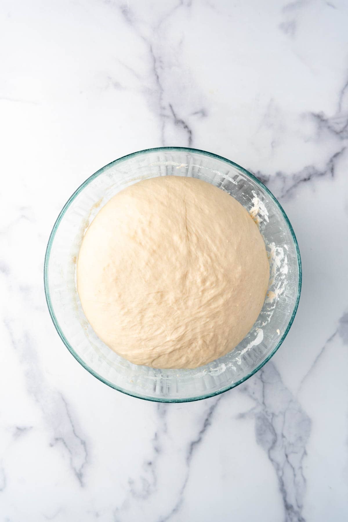 A smooth ball of bagel dough in a bowl.