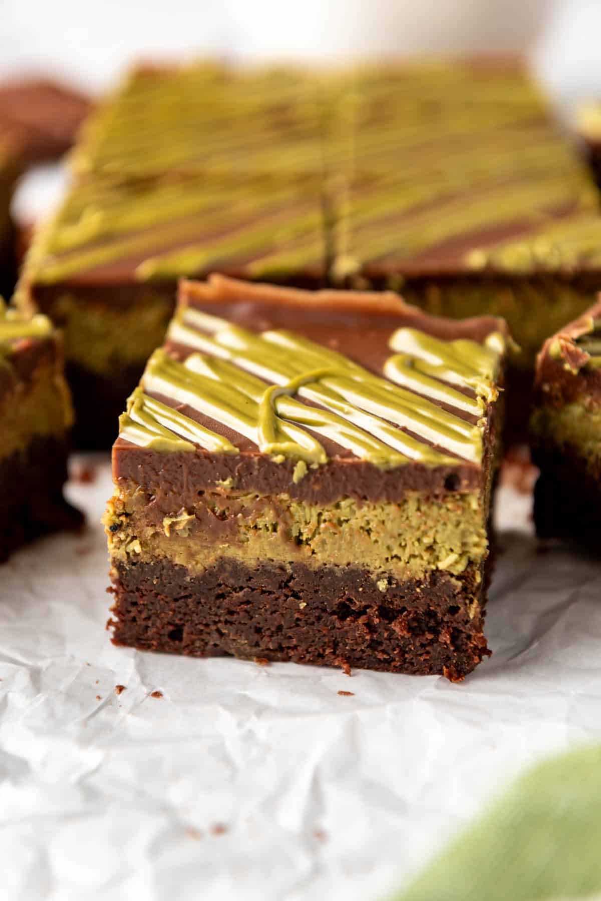 A Dubai chocolate brownie with a layer of crunchy pistachio cream on top of fudgy brownies with chocolate ganache on top.