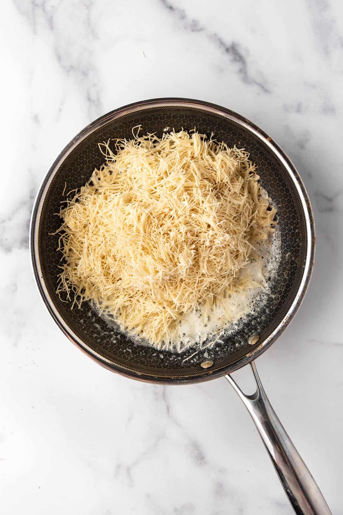 Chopped kataifi in a pan with melted butter.