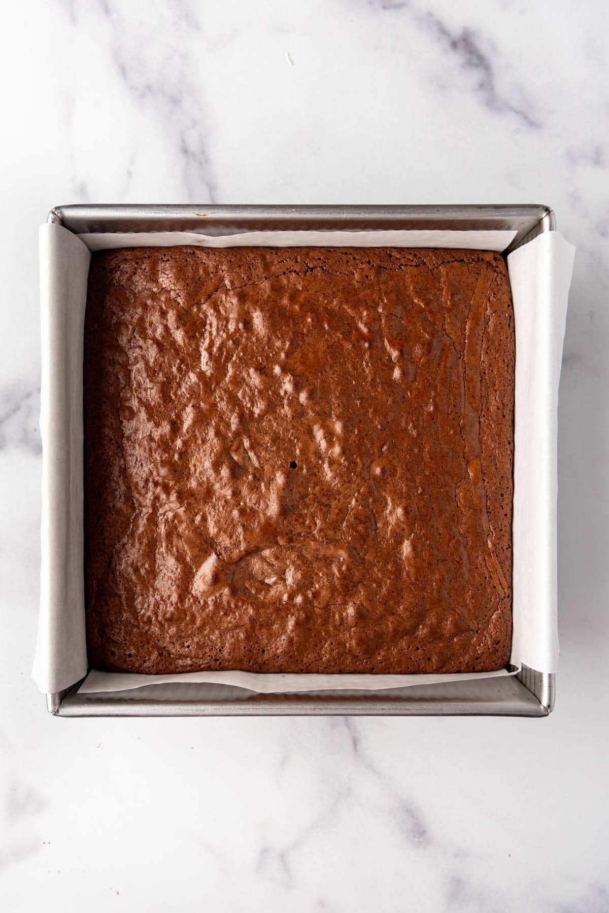 A square pan of homemade fudgy brownies with a shiny, crackly top.