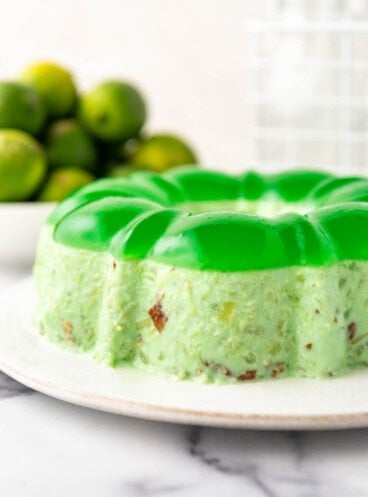 A side angle of a lime green jello mold on a white plate.