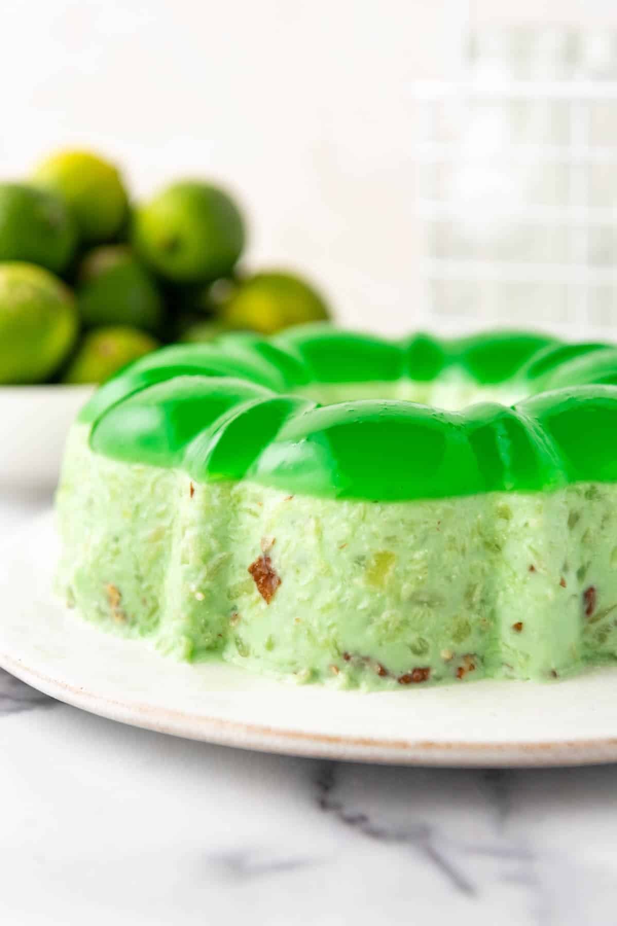 A side angle of a lime green jello mold on a white plate.