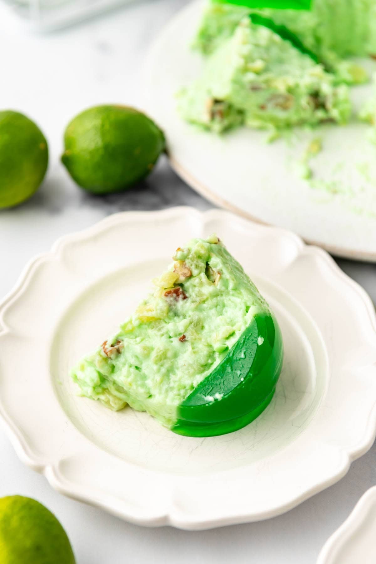 A slice of lime jell-o on a white plate.