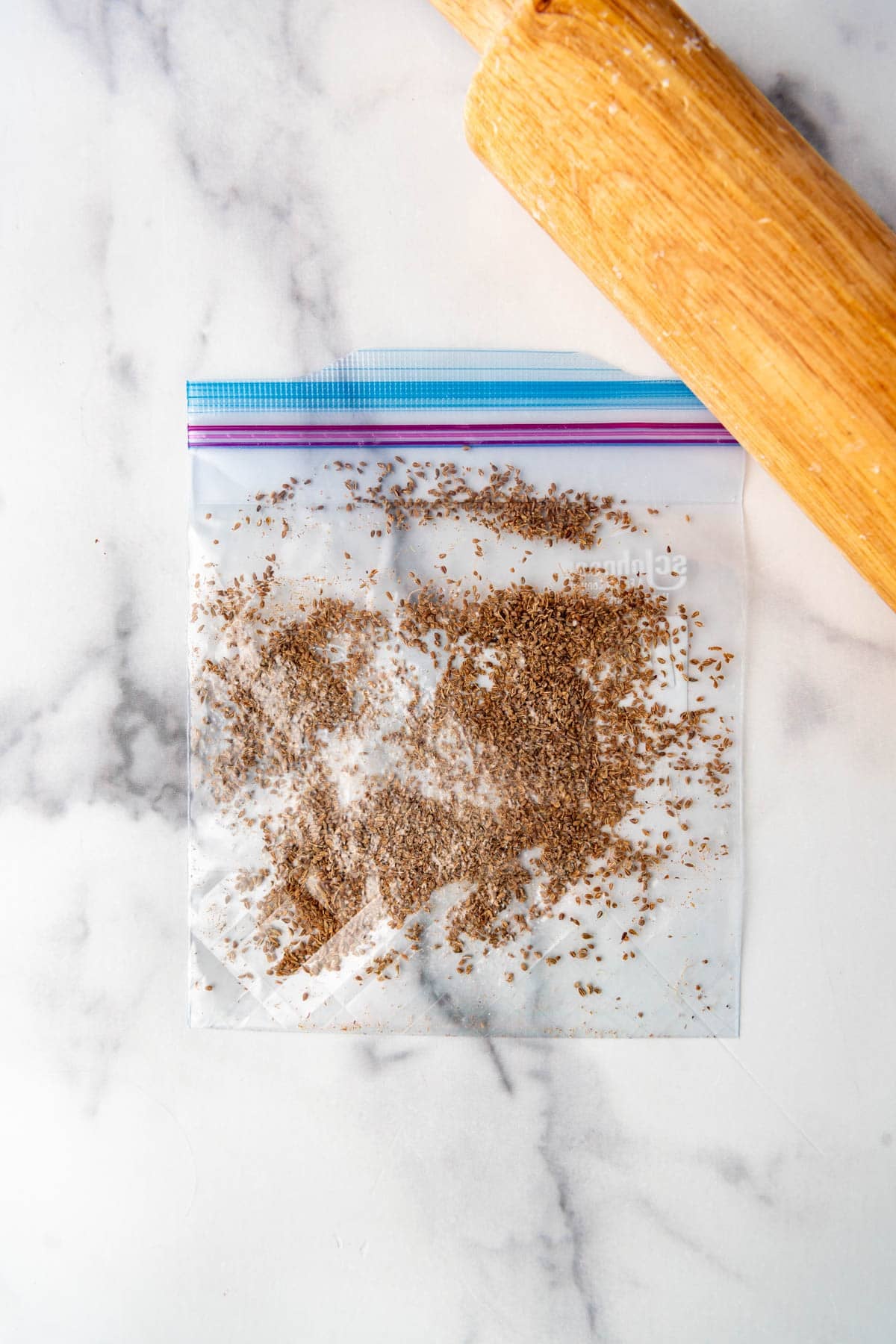 Crushed anise seeds in a zip loc bag with a rolling pin.