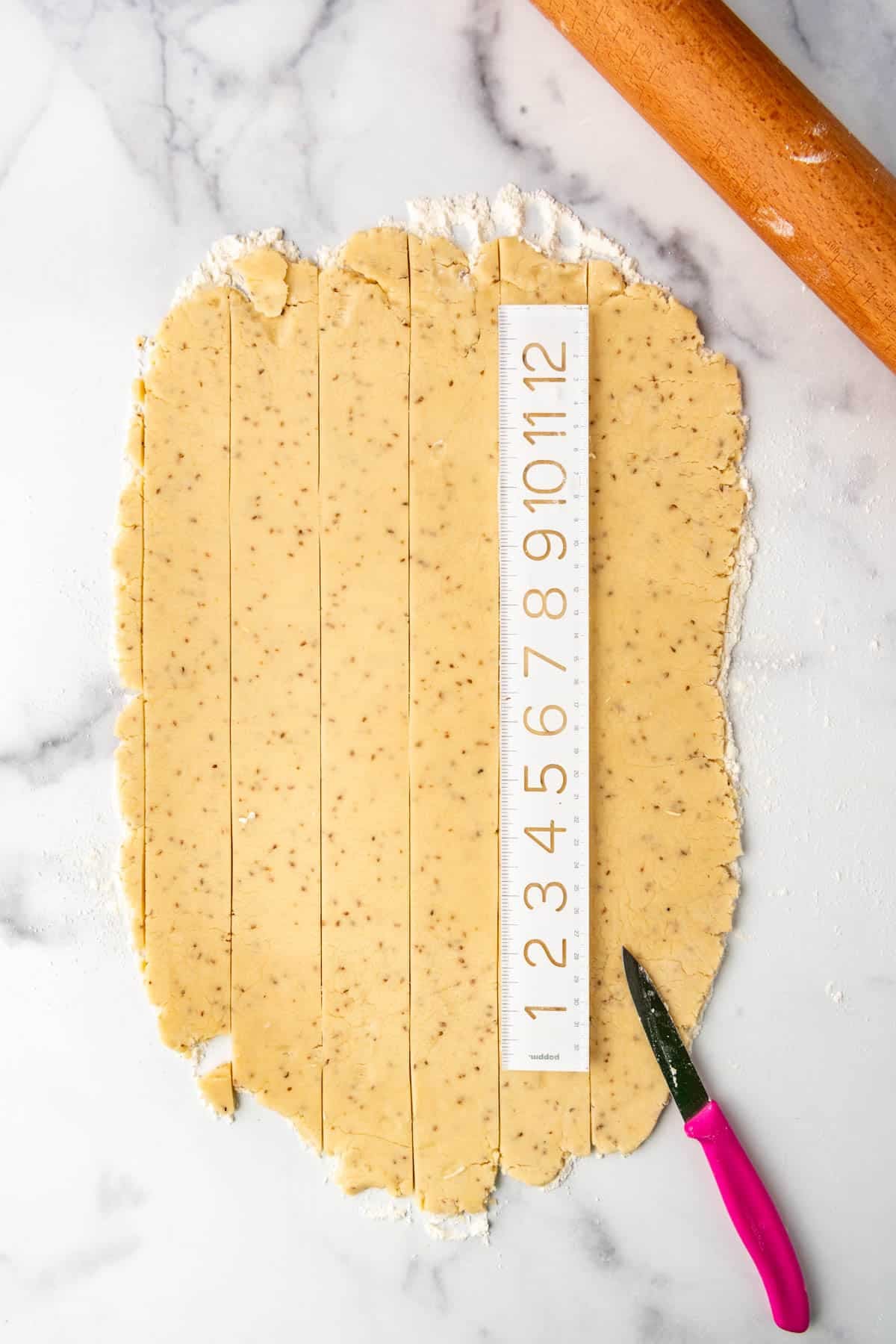 A ruler being used to slice cookie dough into even shapes.