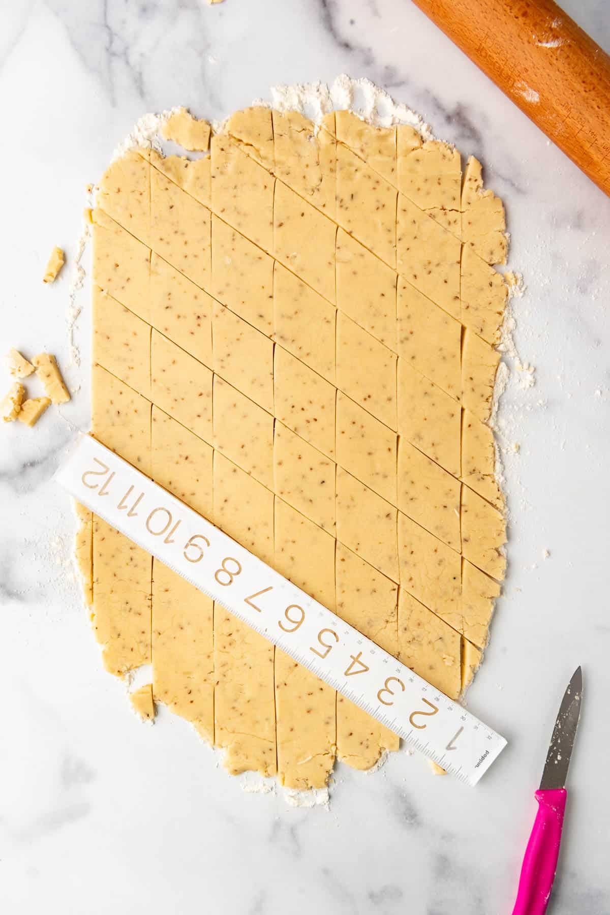 A ruler being used to slice cookie dough into diamond shapes.