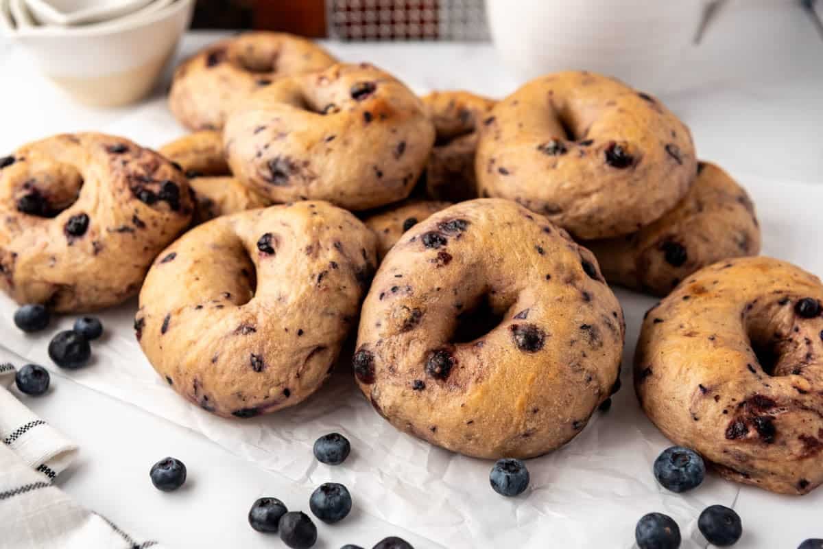Homemade blueberry sourdough bagels stacked in a pile.