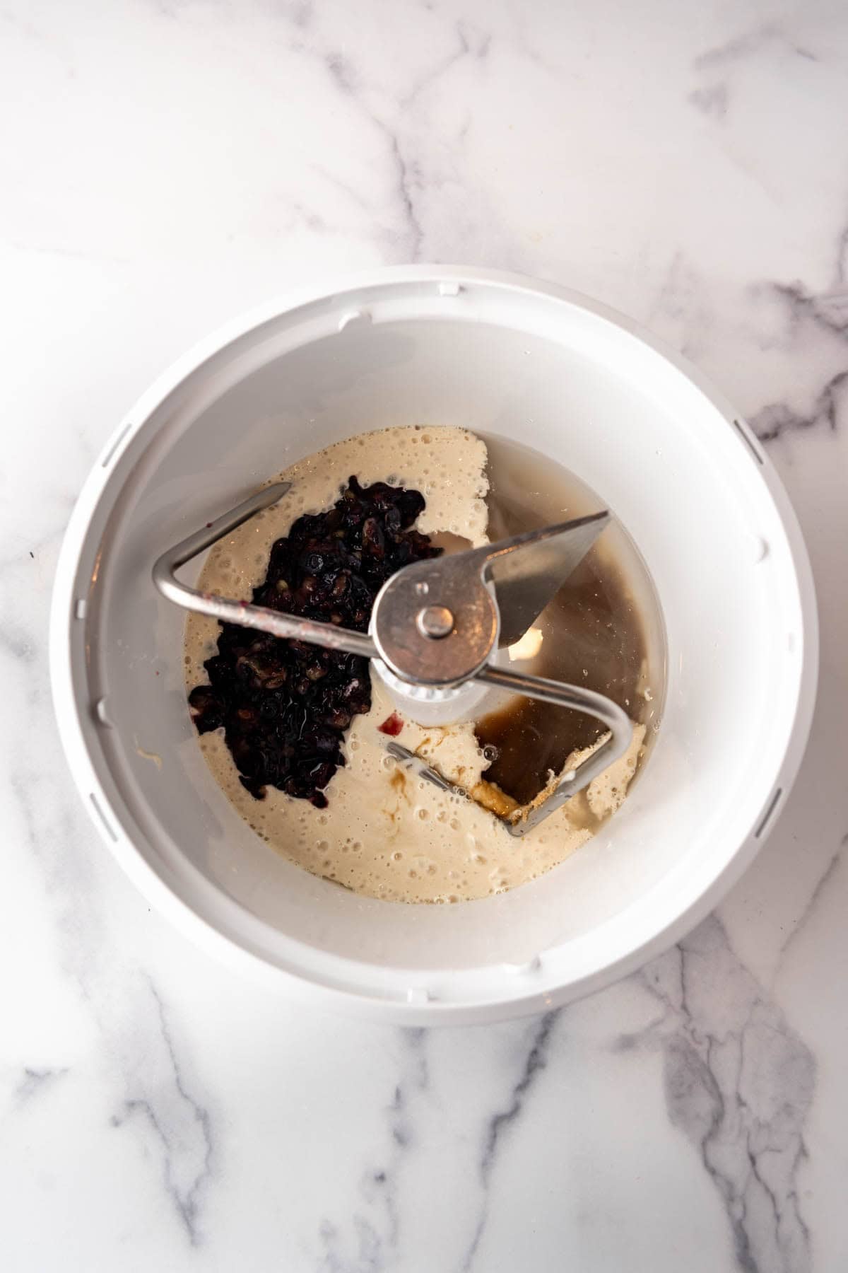 Adding active sourdough starter, mashed blueberries, water, and sugar to a mixer with a dough hook attachment.
