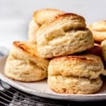 Buttermilk biscuits piled on a plate on a wire cooling rack.