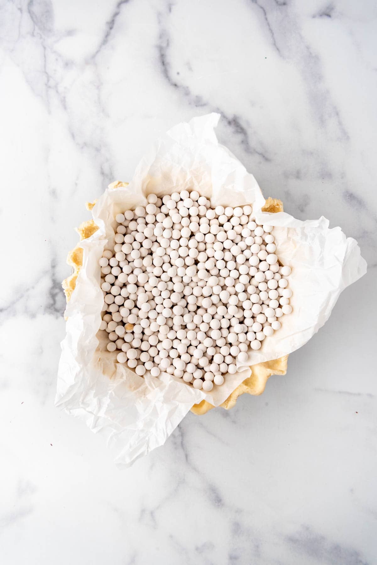 A pie crust filled with pie weights to blind bake it in the oven.