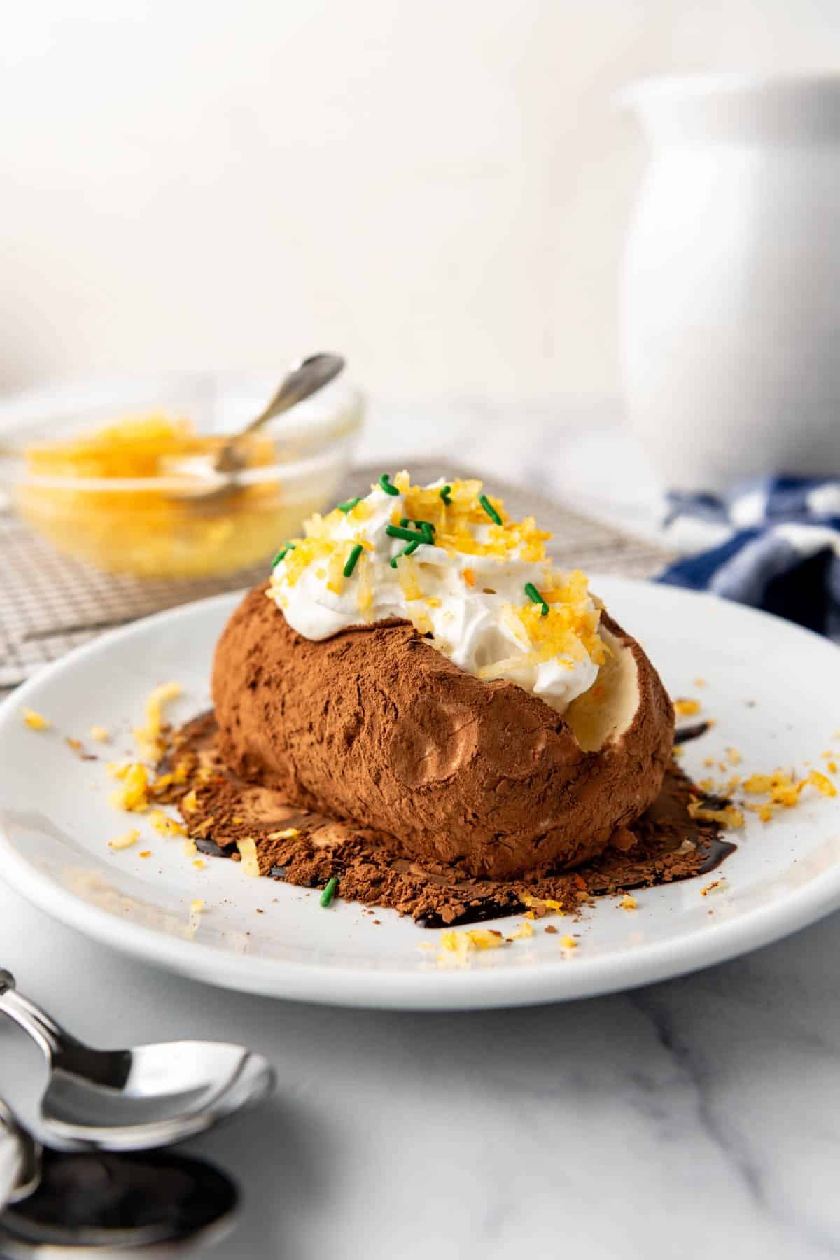 An ice cream dessert decorated to look like a baked potato on a white plate.