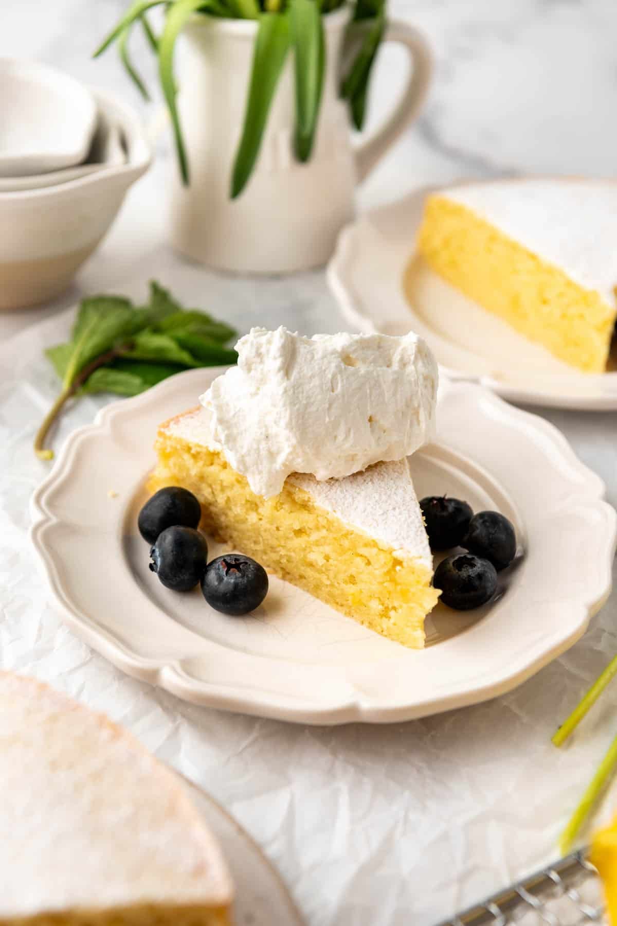A slice of lemon olive oil cake with blueberries and whipped cream.
