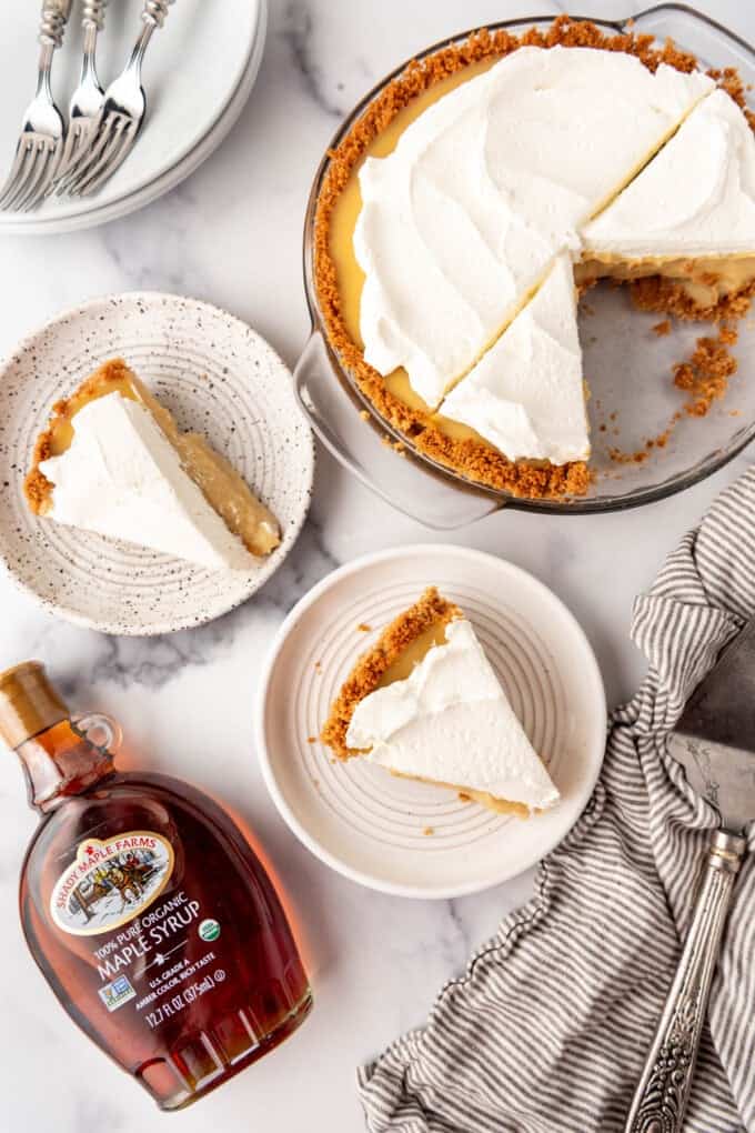 An overhead image of slices of maple cream pie on plates next to a jar of maple syrup.