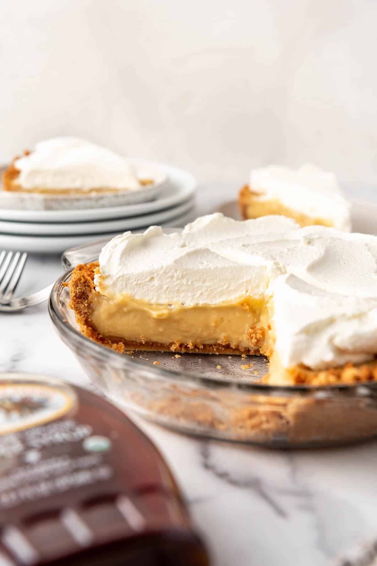A side view of a partially sliced maple cream pie with whipped cream on top.