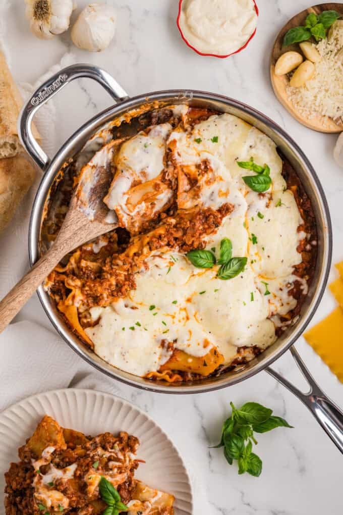An overhead image of a skillet lasagna with a wooden serving spoon in it.