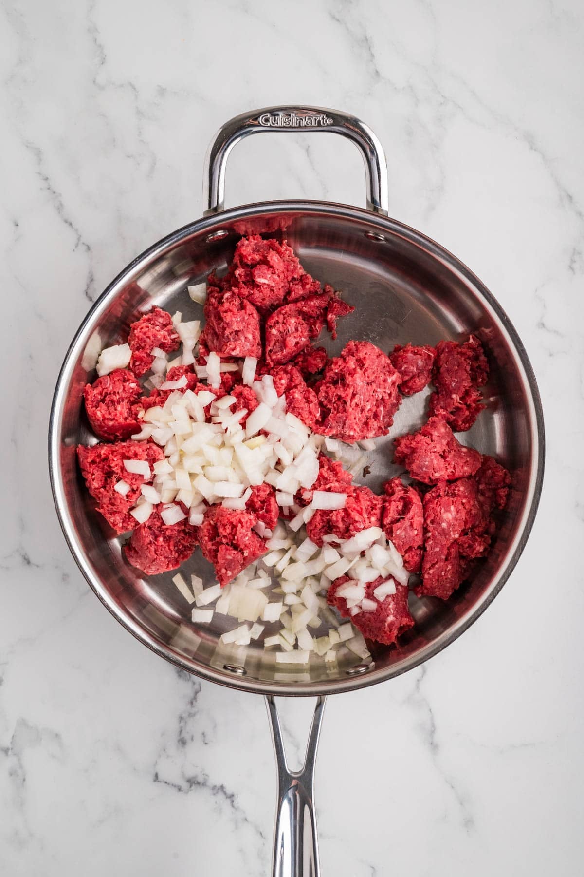 Ground beef and chopped onions in a skillet.
