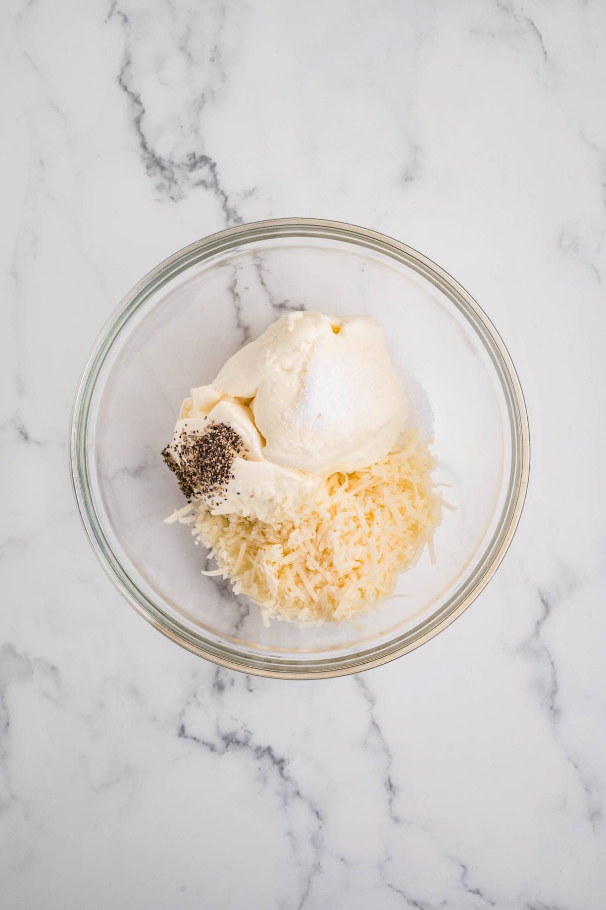 Combining ricotta cheese, grated parmesan, and spices in a bowl.