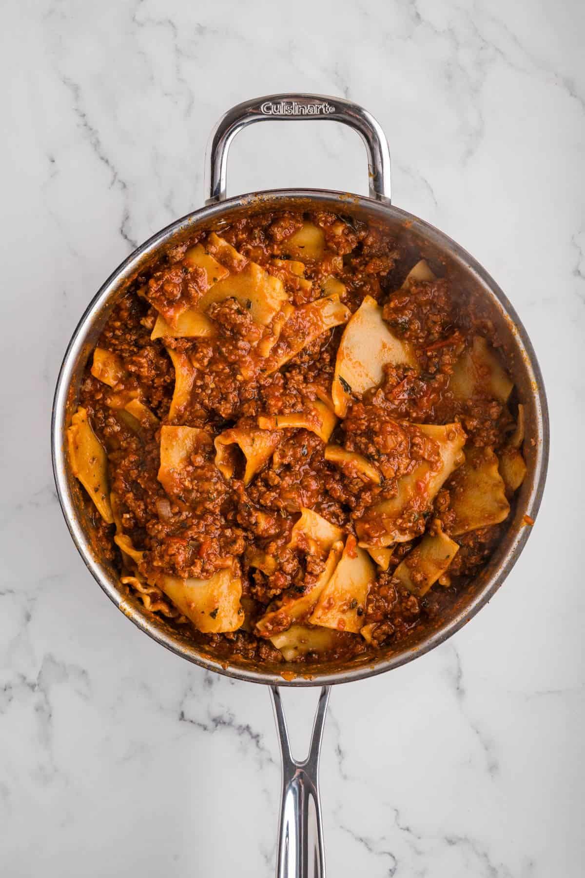 Softened lasagna noodles and meat sauce in a skillet.