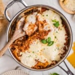 An overhead image of a skillet lasagna with a wooden serving spoon in it.