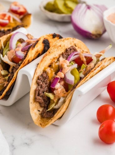 Smash burger tacos in a white taco holder.