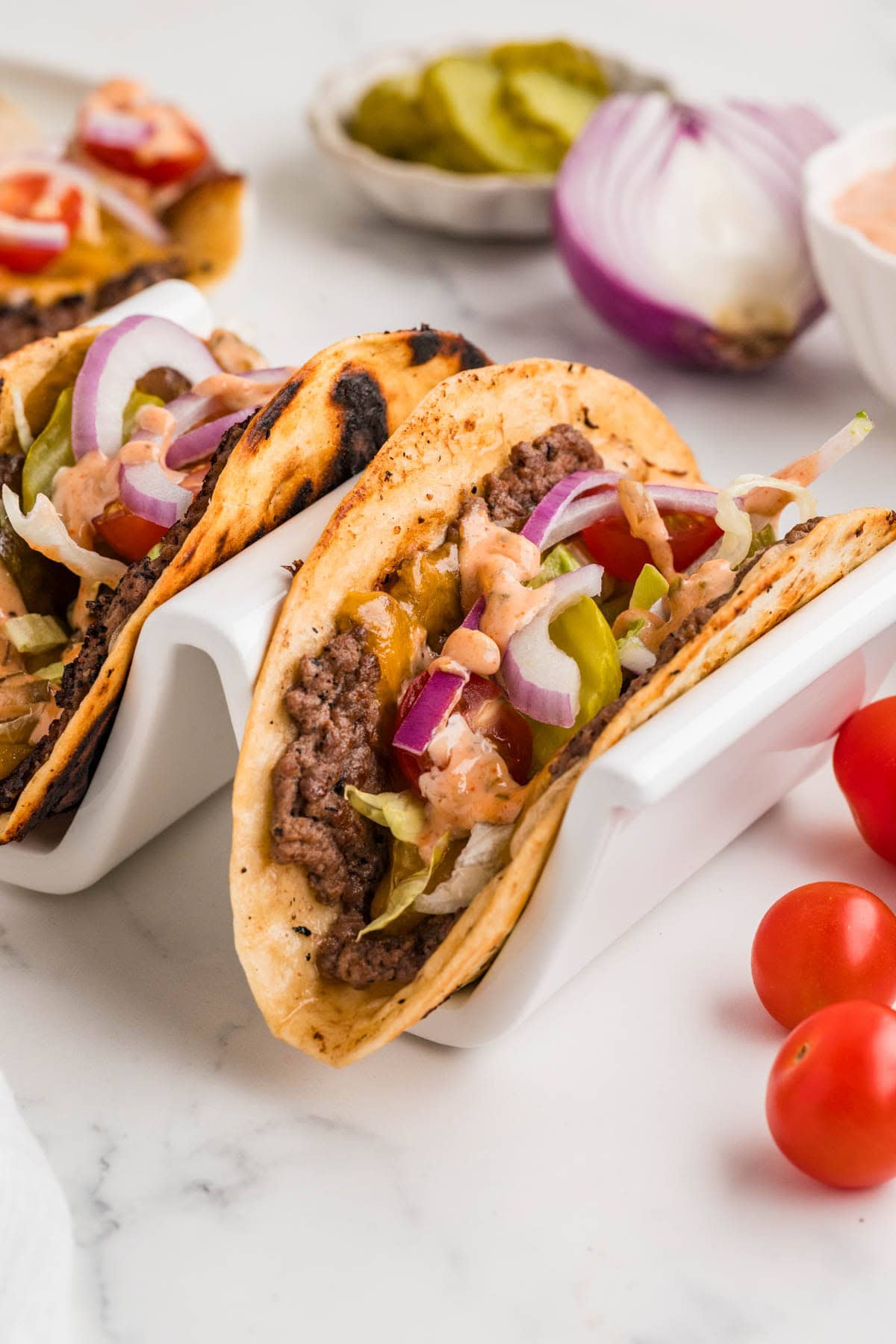 Smash burger tacos in a white taco holder.