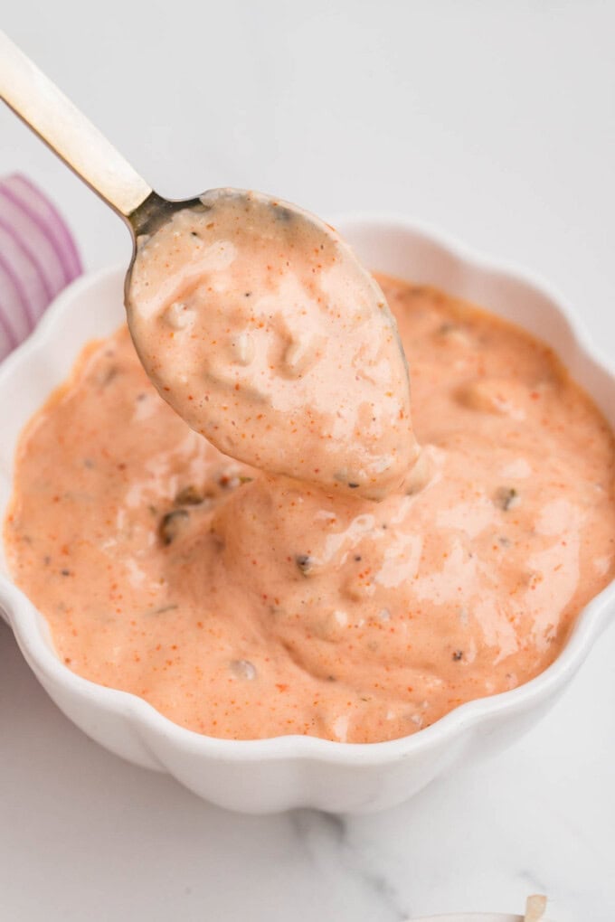 A bowl of burger sauce with a spoon in it.