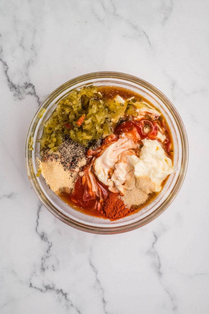 Ingredients like mayo, ketchup, relishes, and spices in a bowl.