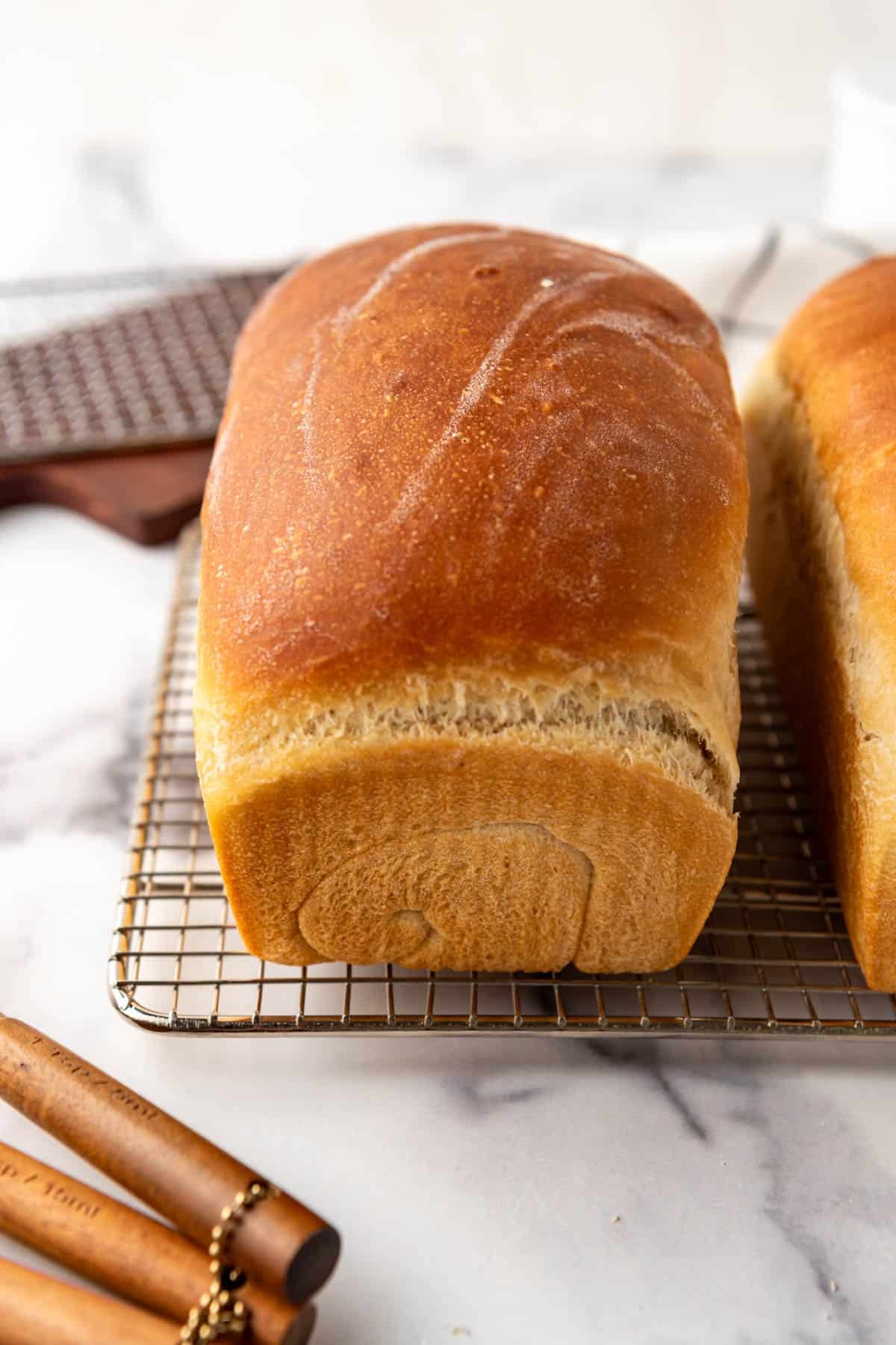 A baked loaf of homemade sourdough sandwich bread with butter rubbed on top.