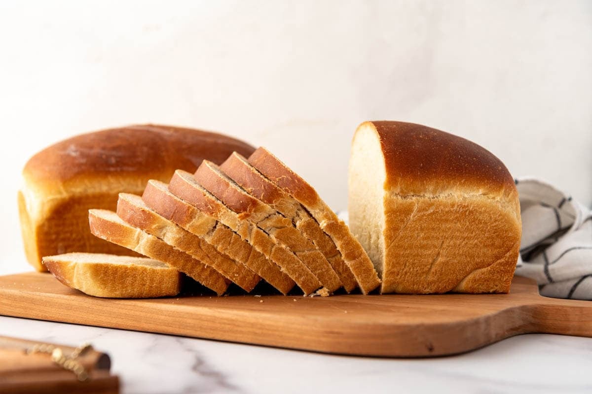 A loaf of sourdough sandwich bread on a wooden cutting board.