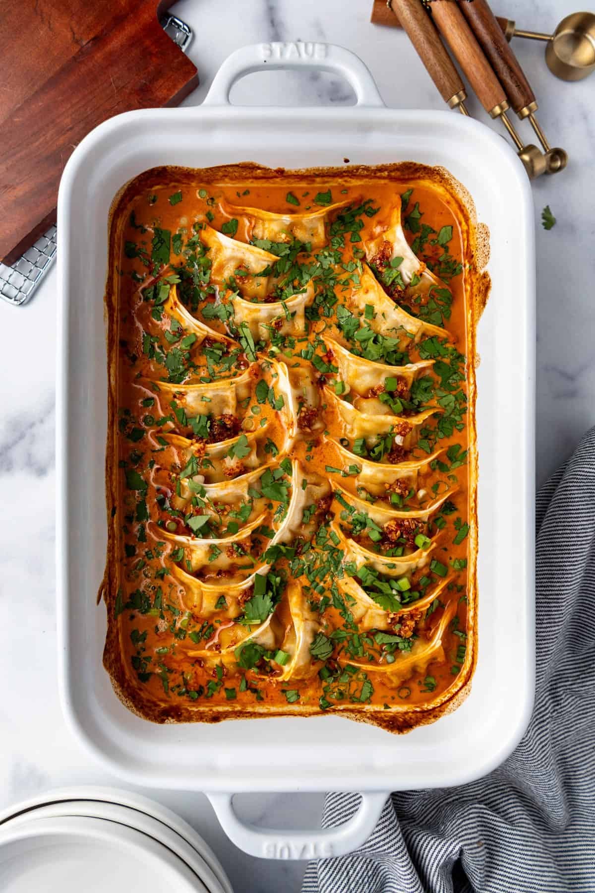 An overhead image of a white casserole dish of the viral TikTok baked dumplings in a red coconut curry sauce.