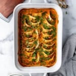 An overhead image of a white casserole dish of the viral TikTok baked dumplings in a red coconut curry sauce.