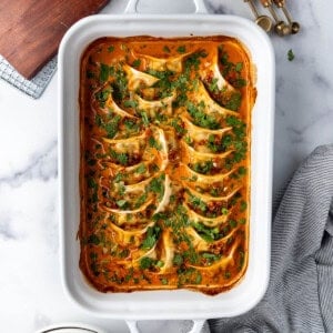 An overhead image of a white casserole dish of the viral TikTok baked dumplings in a red coconut curry sauce.