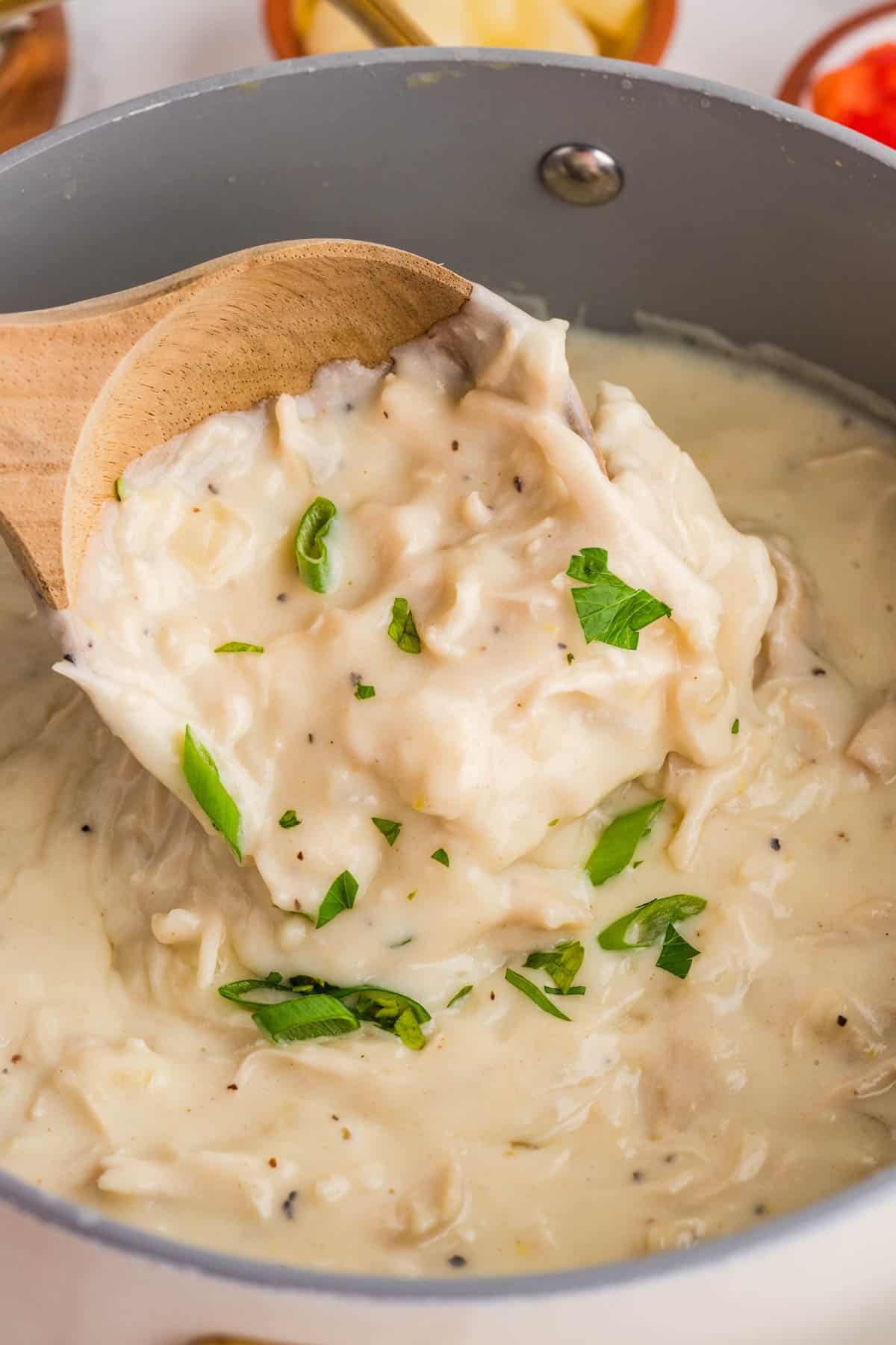 Thick homemade cream of chicken soup with a wooden spoon.
