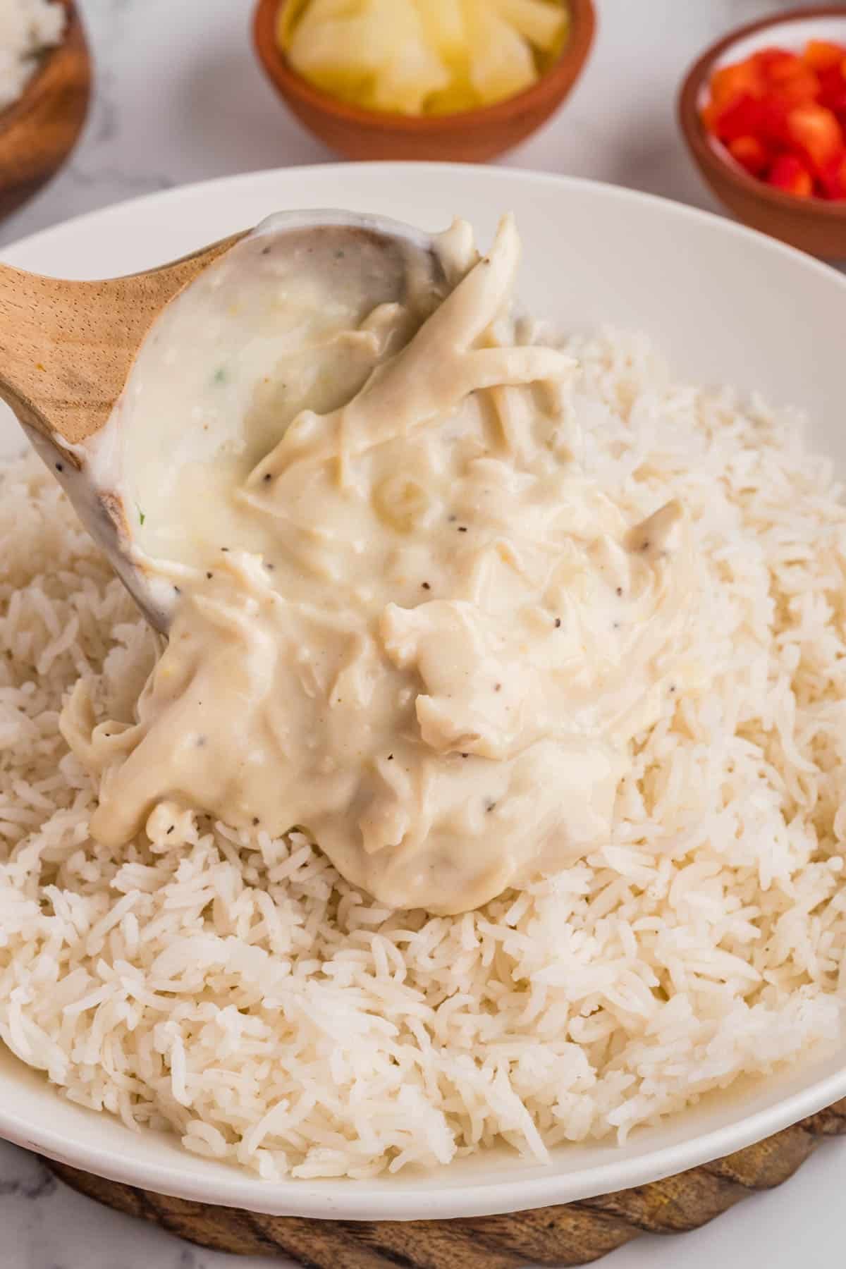 Spooning creamy chicken sauce over a bed of rice.