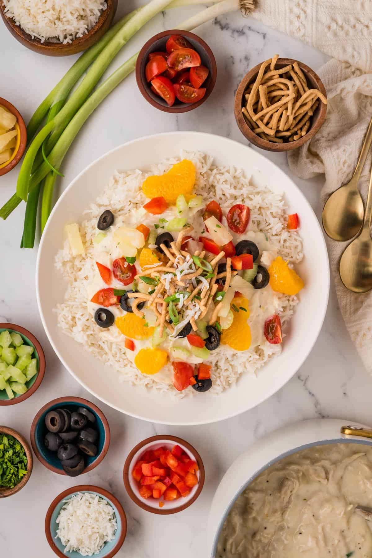 An overhead image of a Hawaiian haystacks bowl with toppings scattered around it.