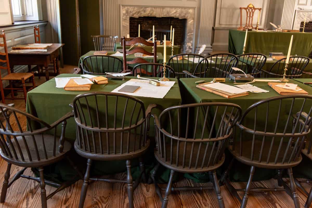 An image of tables covered in green cloth and chairs in Independence Hall where the Founding Fathers signed the U.S. Constitution.