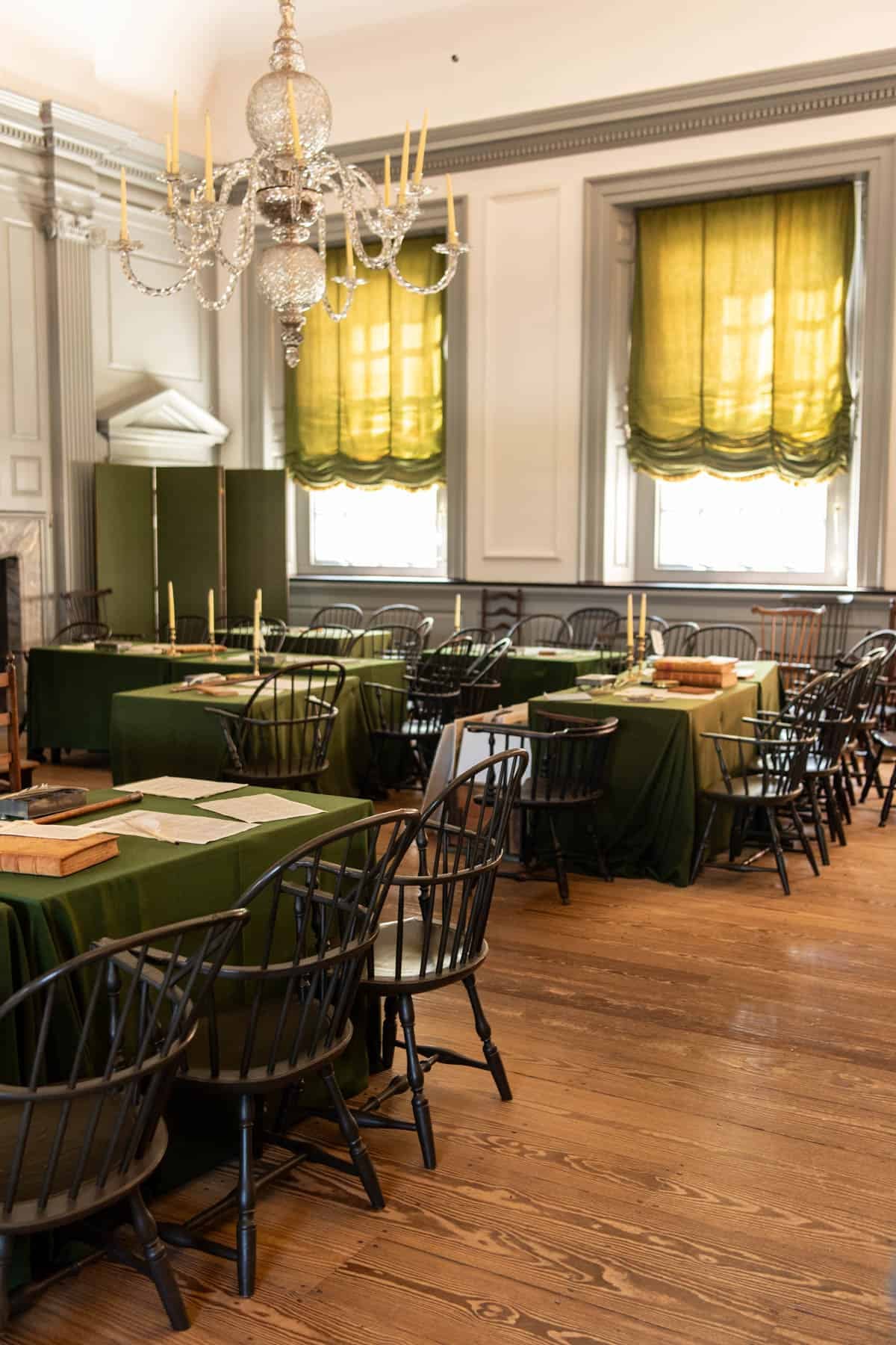 An image of tables covered in green cloth and chairs in Independence Hall where the Founding Fathers signed the U.S. Constitution.