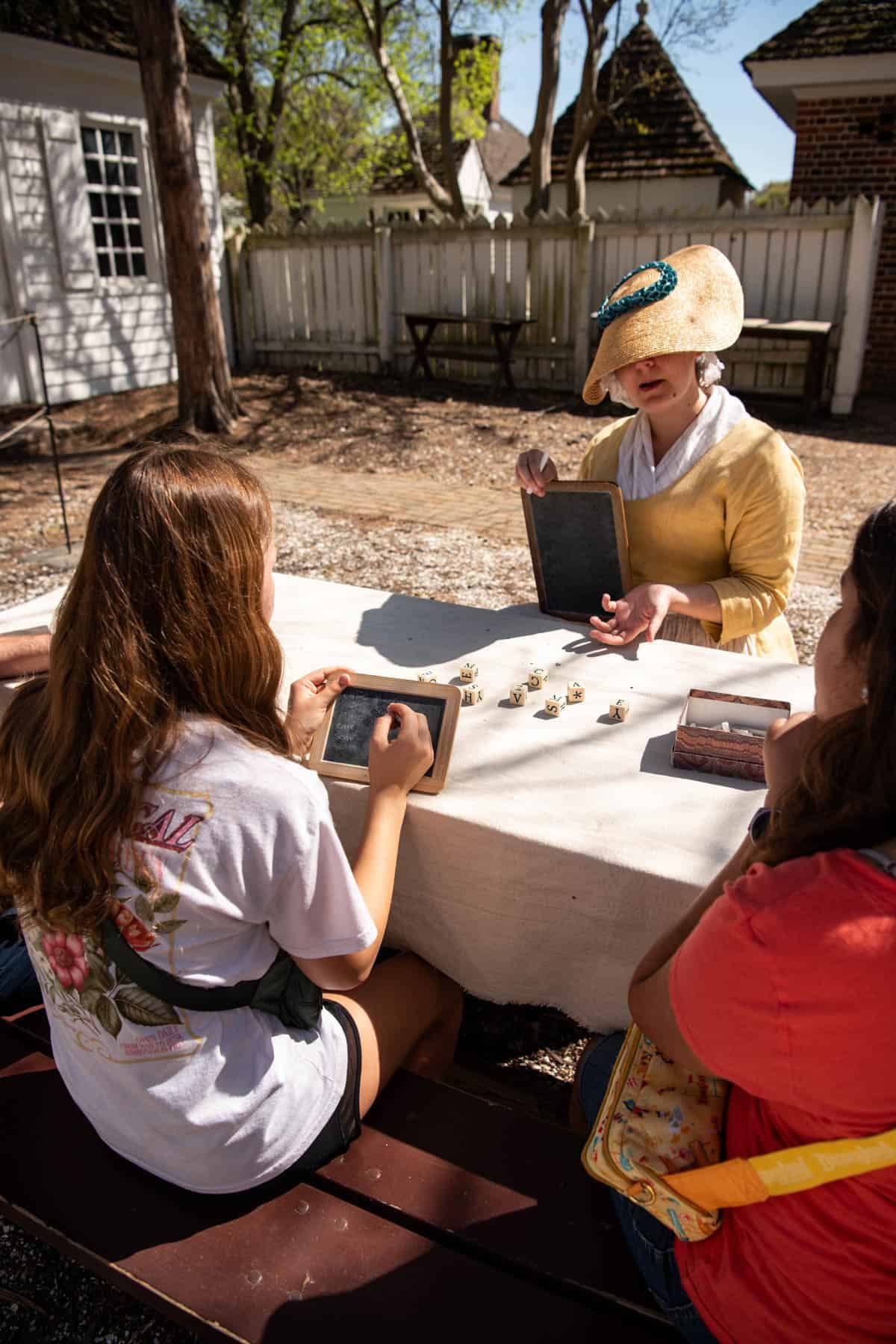 An image of a family playing games popular in colonial America with a living history actress in Colonial Williamsburg.