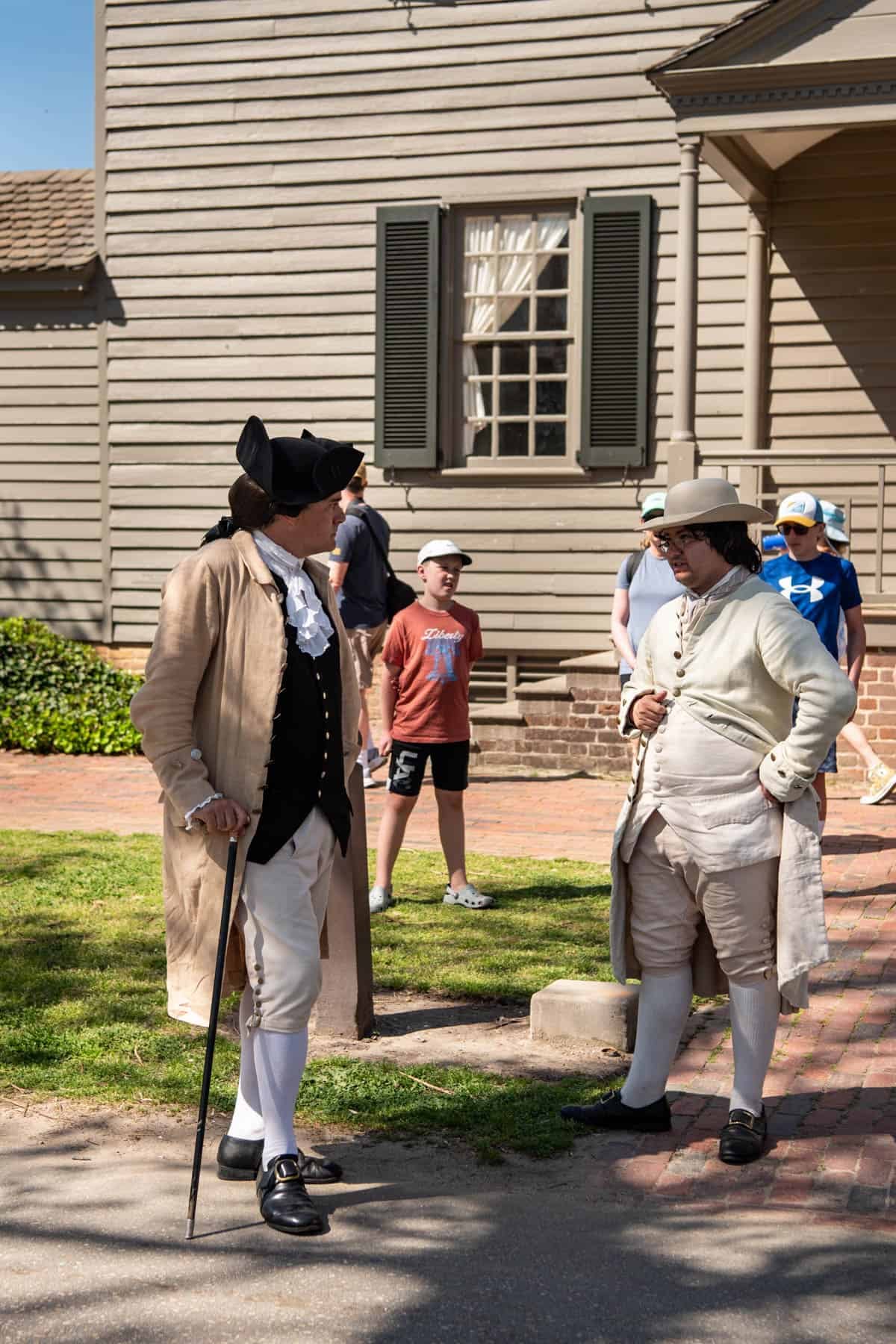 Two actors in colonial attire standing on the street in Colonial Williamsburg, Virginia.