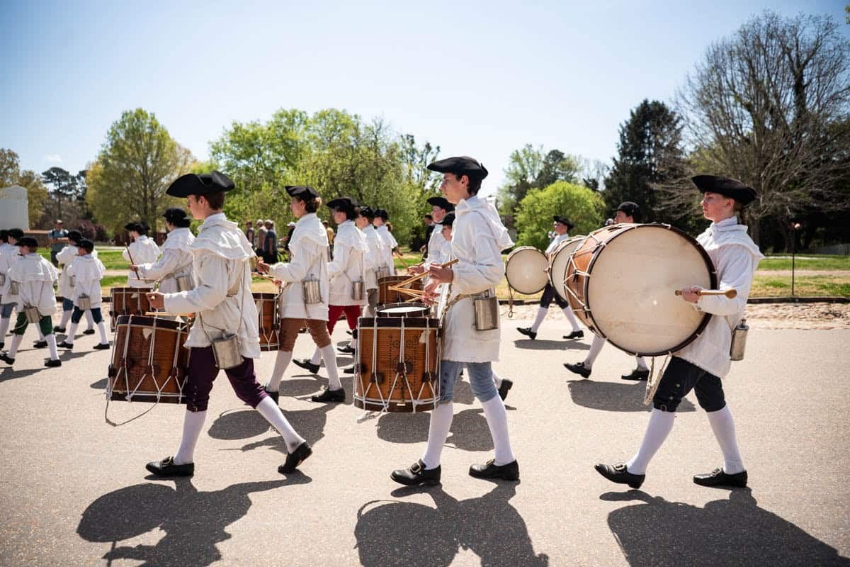 A group of drummers in colonial era attire marching in Colonial Williamsburg.