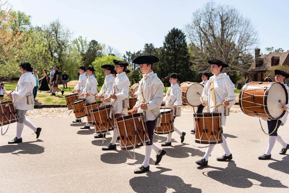 A group of drummers in colonial era attire marching in Colonial Williamsburg.