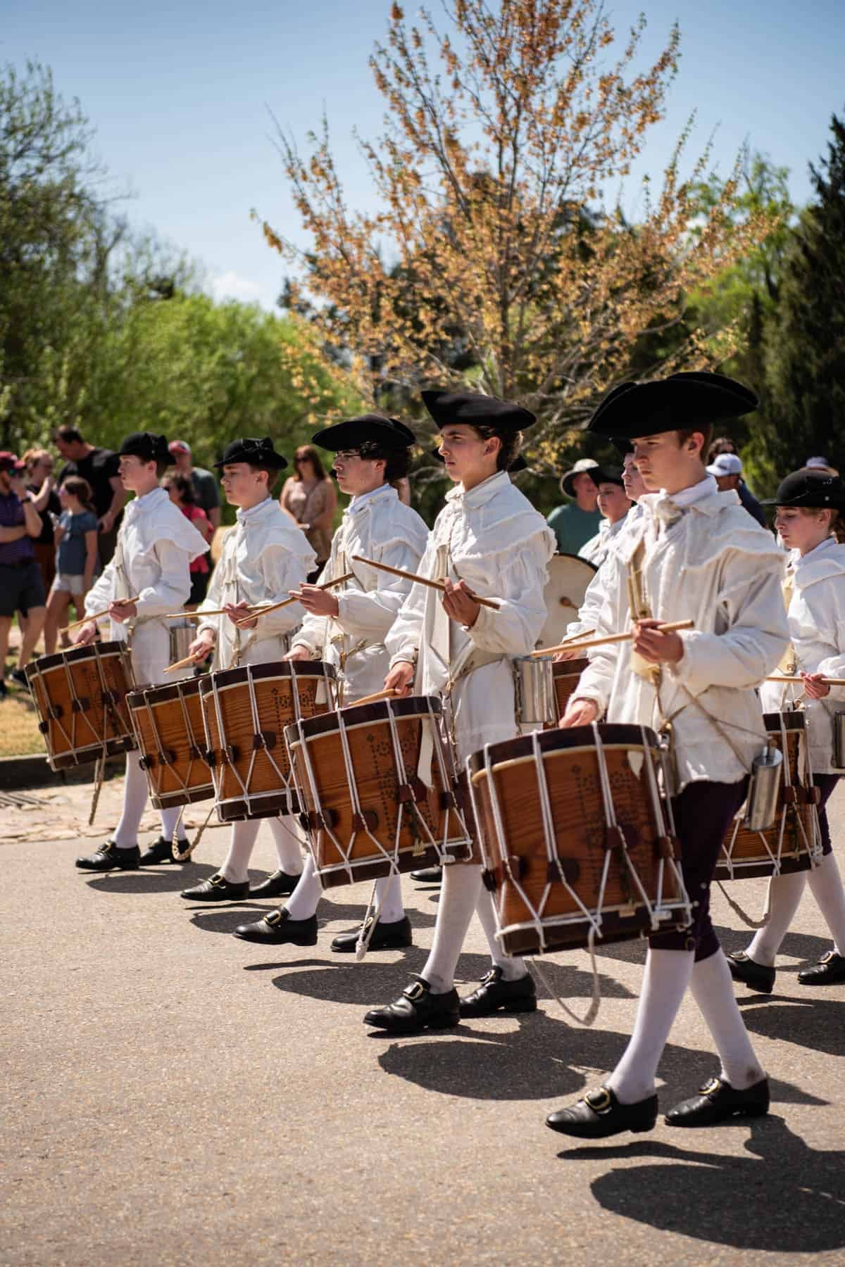 A group of drummers in colonial era attire marching in Colonial Williamsburg.