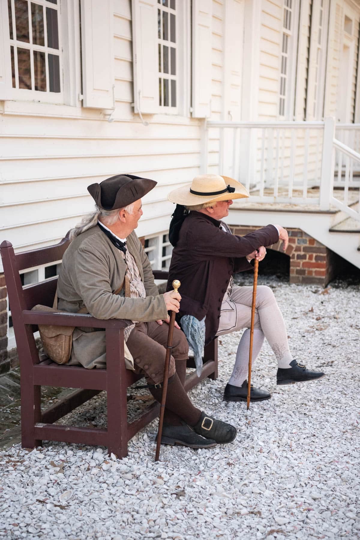 Two men dressed in colonial America era clothing sitting on a bench in Williamsburg, Virginia.